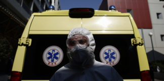 Νοσηλευτής με μαπ για covid-19 μπροστά από ασθενοφόρο
