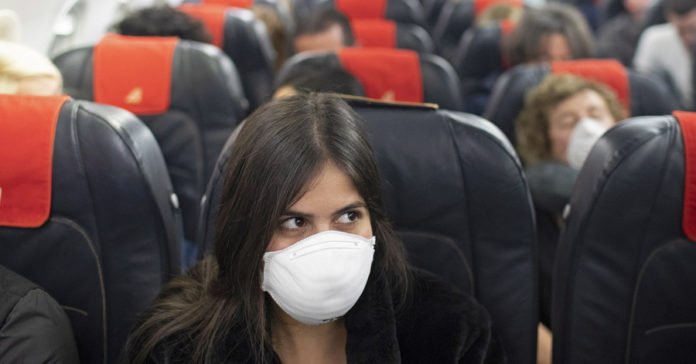 Επιβάτης σε αεροπλάνο φορώντας μάσκα προστασίας