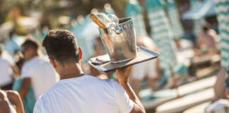 Σερβιτόρος με δίσκο και σαμπάνια σε beach bar