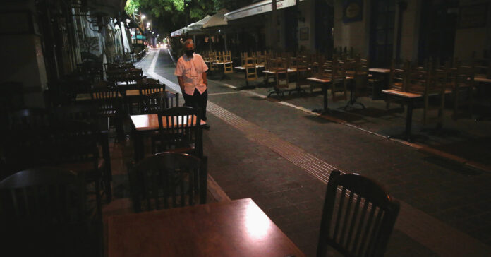 Σερβιτόρος μπροστά από άδεια τραπέζια στο Μοναστηράκι